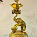 Gold brass statue of a mythical serpent atop a decorative bowl, perched on a round, engraved base on a marble surface.  thebrasshandicrafts.com
