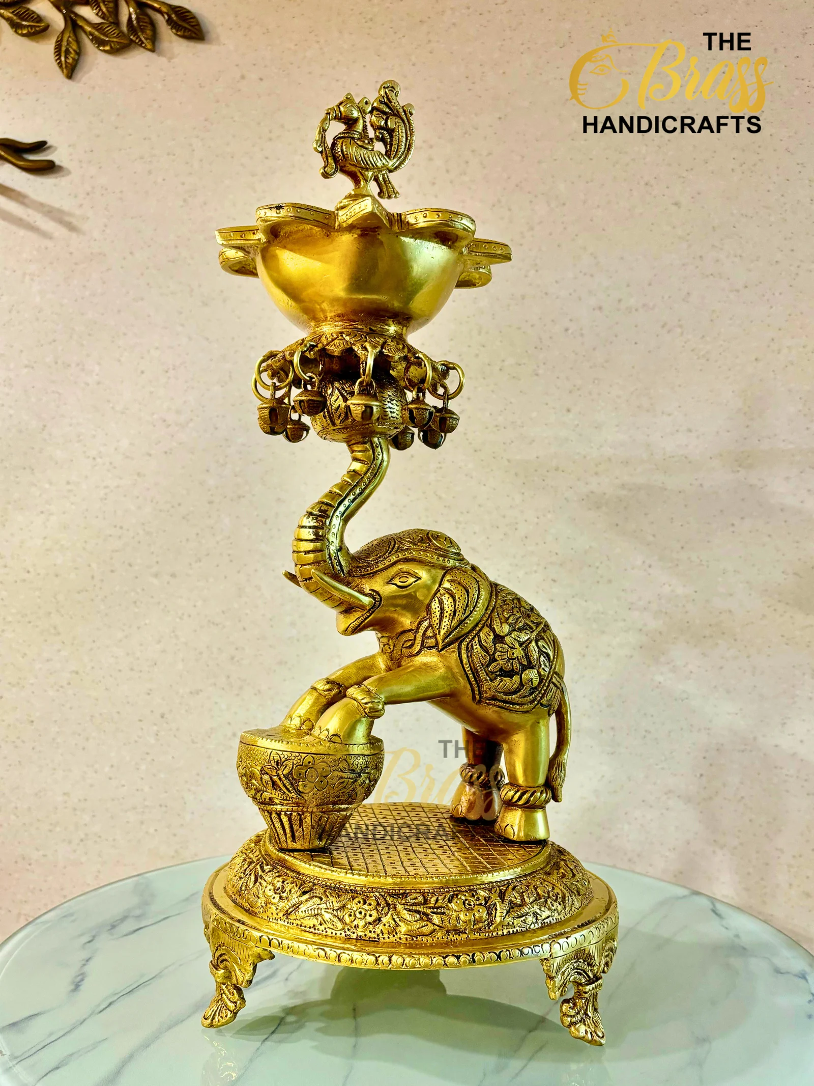 Gold brass statue of a mythical serpent atop a decorative bowl, perched on a round, engraved base on a marble surface.  thebrasshandicrafts.com