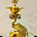 Ornate gold brass lamp with a sculpted bird finial on top and hanging decorative bells beneath.  thebrasshandicrafts.com