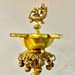 Close-up of an ornate gold brass lamp with a decorative bird-shaped finial on top, highlighting its detailed craftsmanship.  thebrasshandicrafts.com