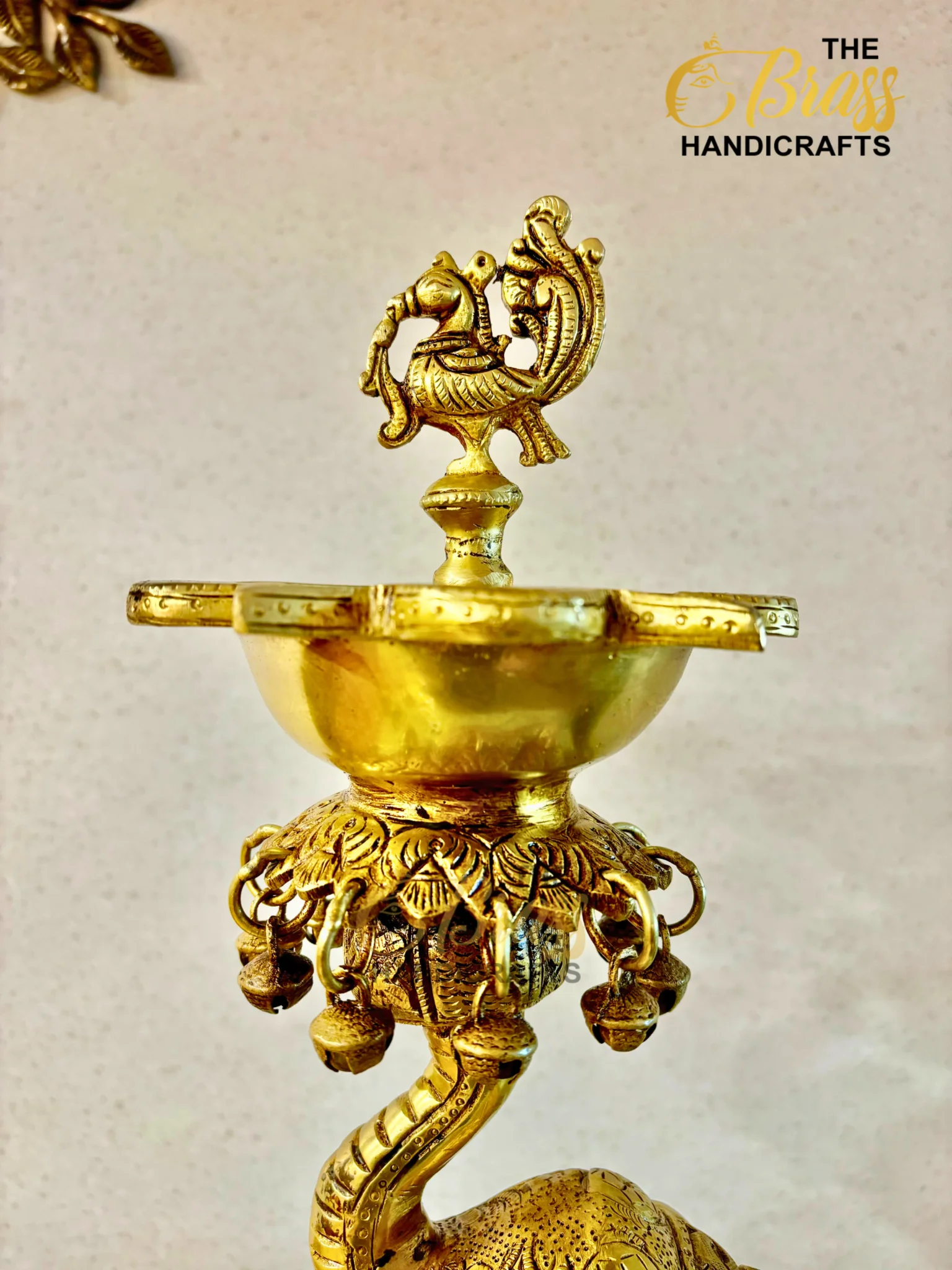 Close-up of an ornate gold brass lamp with a decorative bird-shaped finial on top, highlighting its detailed craftsmanship.  thebrasshandicrafts.com