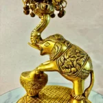 Ornate gold brass bird statue with a curved neck, decorative bells, and a patterned pedestal.  thebrasshandicrafts.com