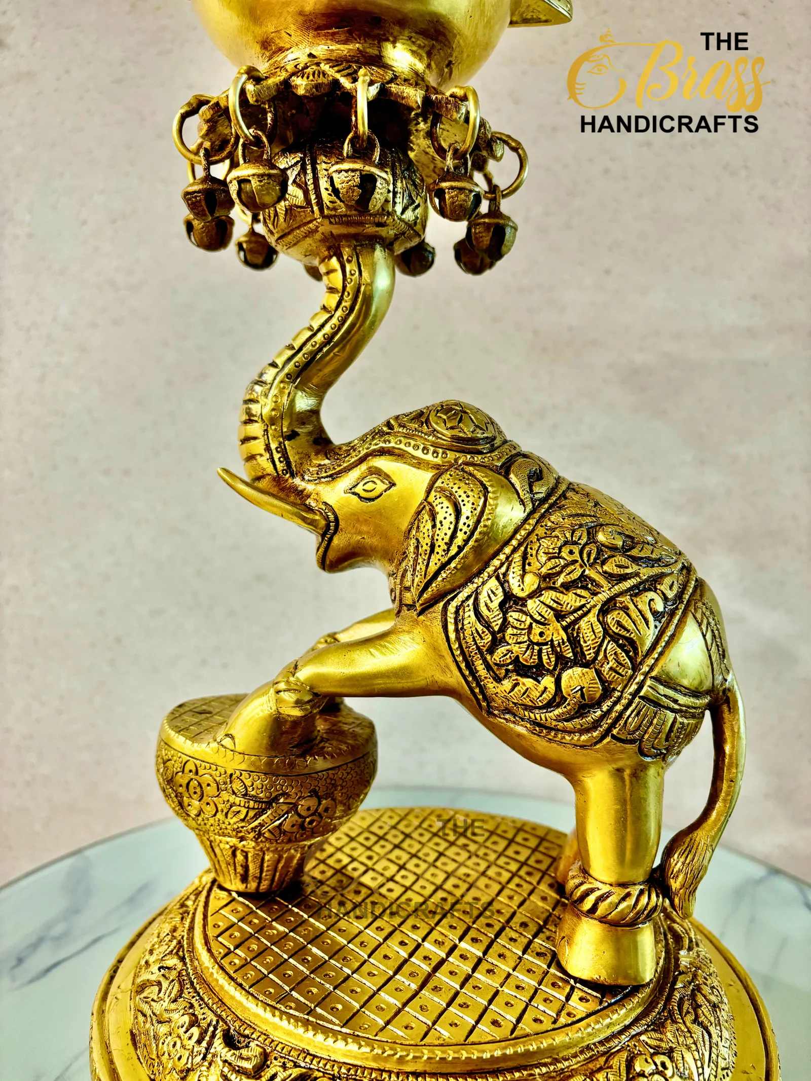Ornate gold brass bird statue with a curved neck, decorative bells, and a patterned pedestal.  thebrasshandicrafts.com