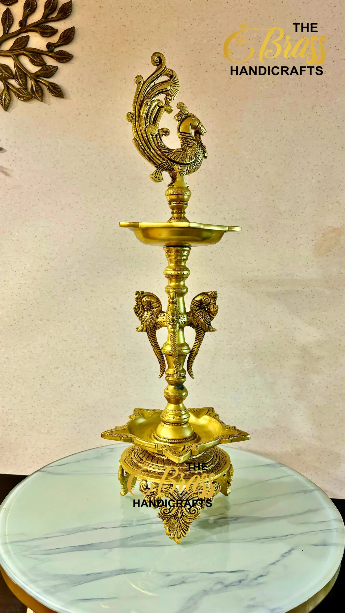 Ornate brass hookah with a peacock finial stands on a marble-topped table, logo 'The Brass Handicrafts' in the corner.  thebrasshandicrafts.com