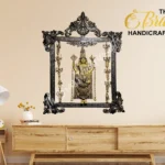 Ornate black frame containing a gold Hindu deity statue on a beige wall, with The Brass Handicrafts logo in the top right place.  thebrasshandicrafts.com