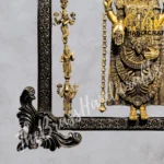 Ornate gold Hindu deity statue inside a decorative black framed display with hanging bead garlands.  thebrasshandicrafts.com
