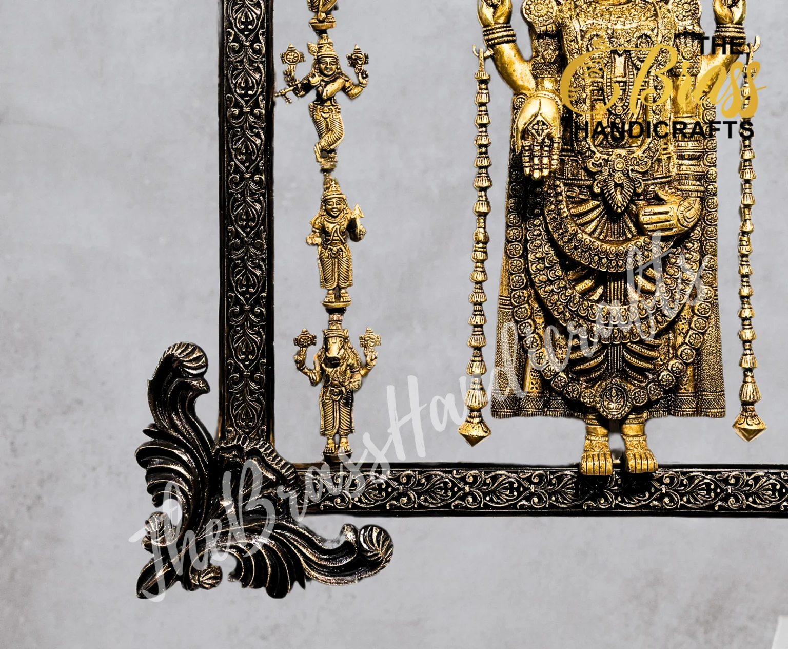 Ornate gold Hindu deity statue inside a decorative black framed display with hanging bead garlands.  thebrasshandicrafts.com