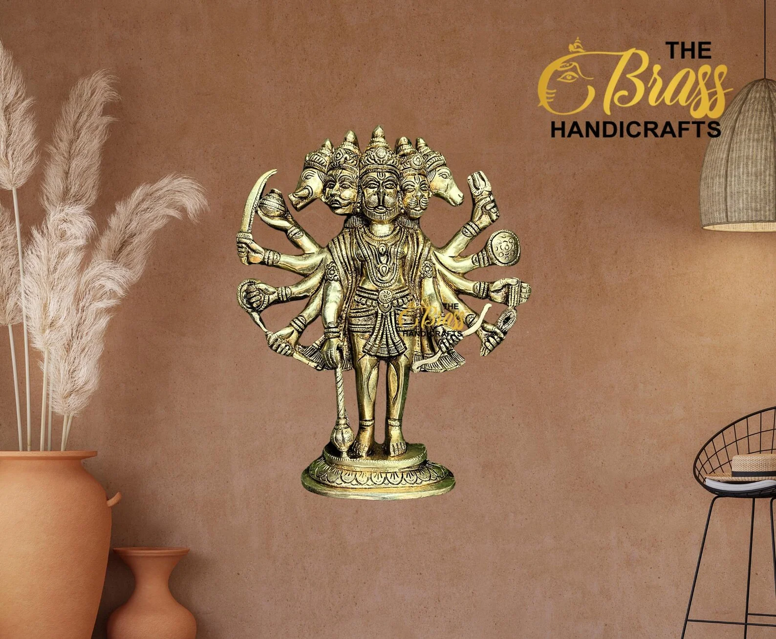 Brass multi-armed Hindu deity statue displayed in a home decor setting with a warm brown wall and The Brass Handicrafts logo in the corner.  thebrasshandicrafts.com