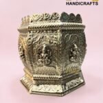 Ornate silver decorative box with embossed figures and floral patterns against a pink background.  thebrasshandicrafts.com