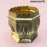 Ornate crown-shaped brass handicraft with intricate scrollwork on a pink background, logo in corner reads 'The Brass Handicrafts'.  thebrasshandicrafts.com