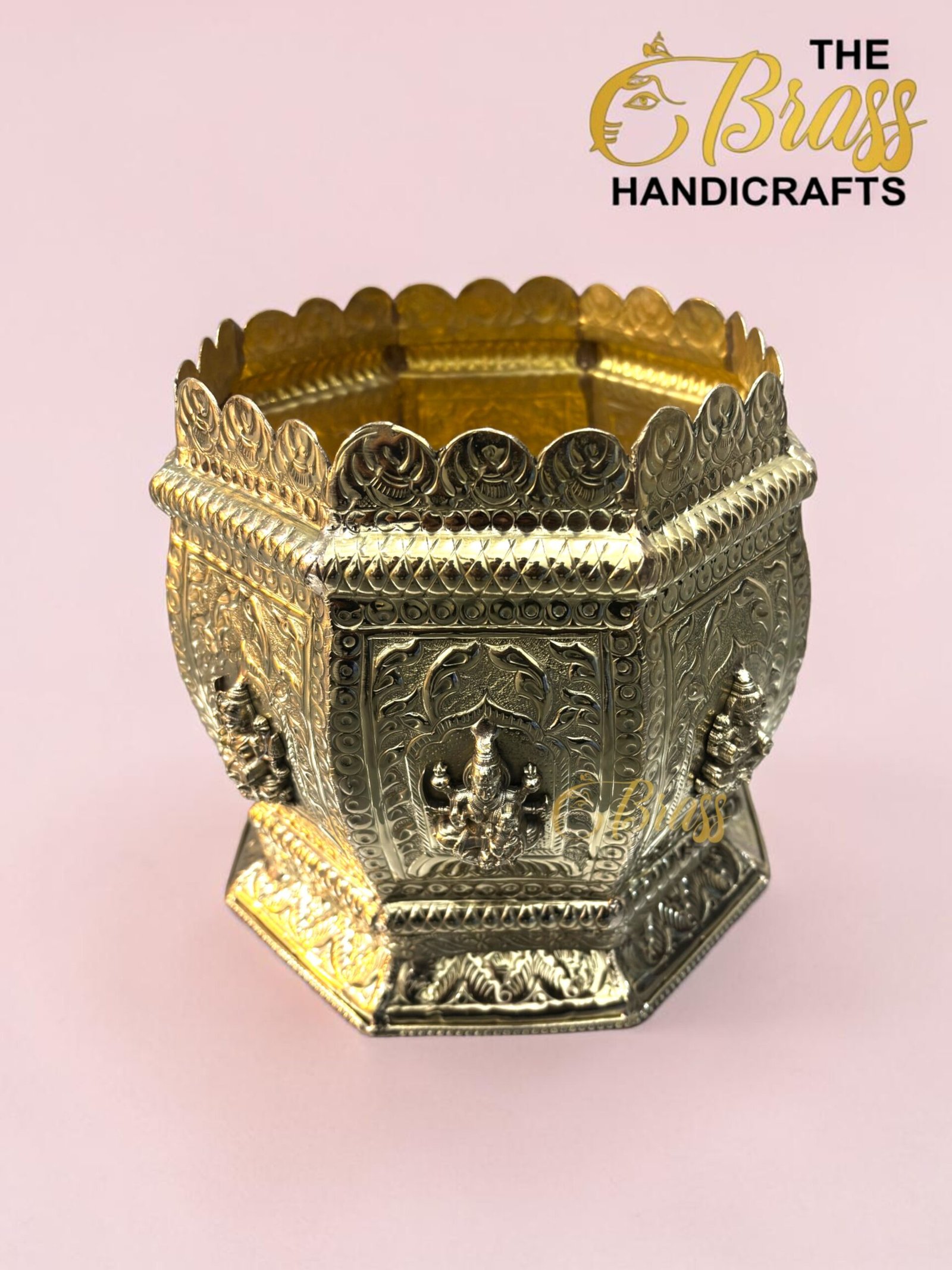 Ornate crown-shaped brass handicraft with intricate scrollwork on a pink background, logo in corner reads 'The Brass Handicrafts'.  thebrasshandicrafts.com