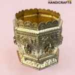 Ornate gold-toned metal decorative crown-like vessel with embossed patterns on a pink backdrop  thebrasshandicrafts.com