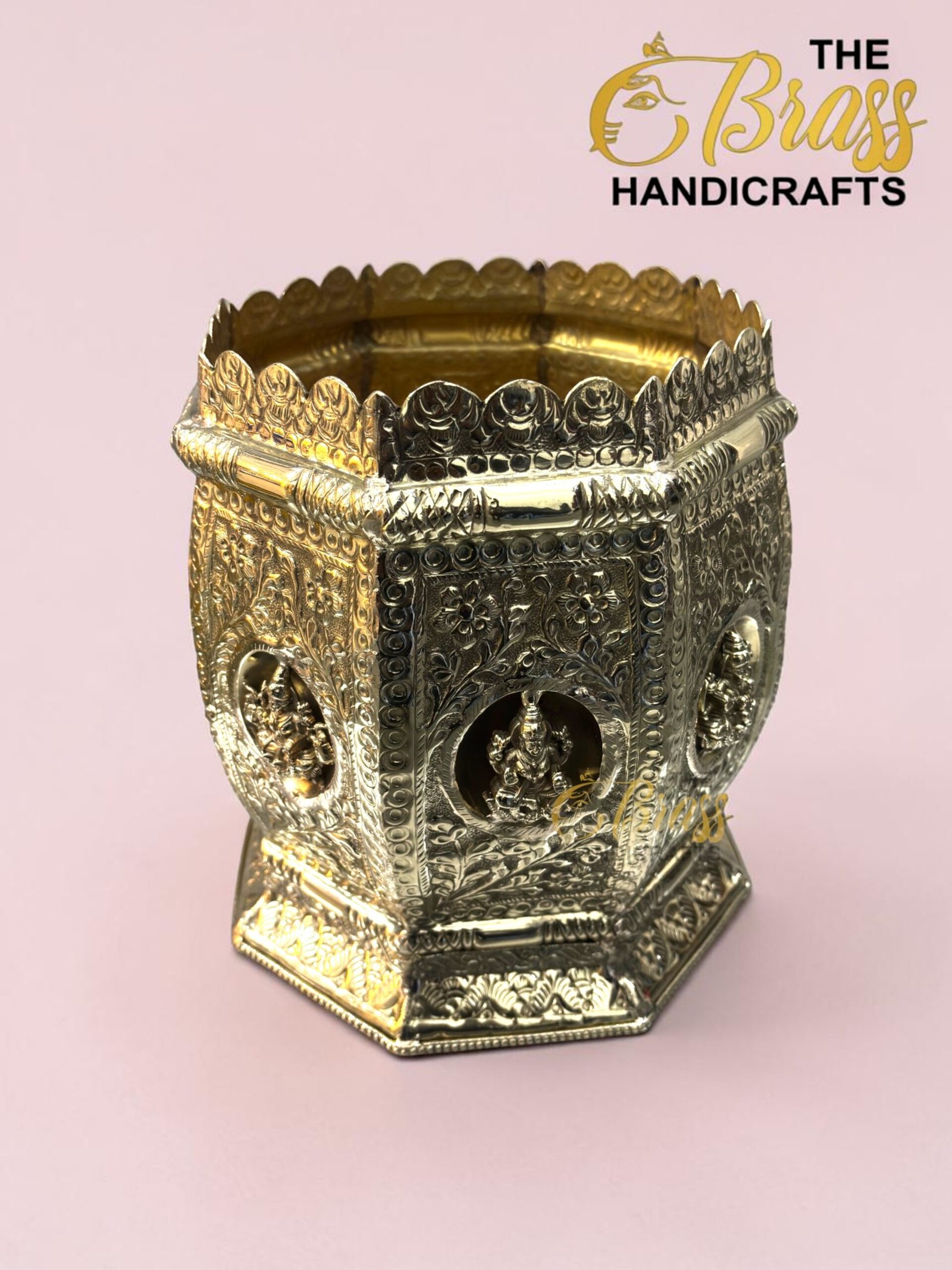 Ornate brass decorative container with a scalloped crown-like rim and intricate floral engravings against a pink background.  thebrasshandicrafts.com