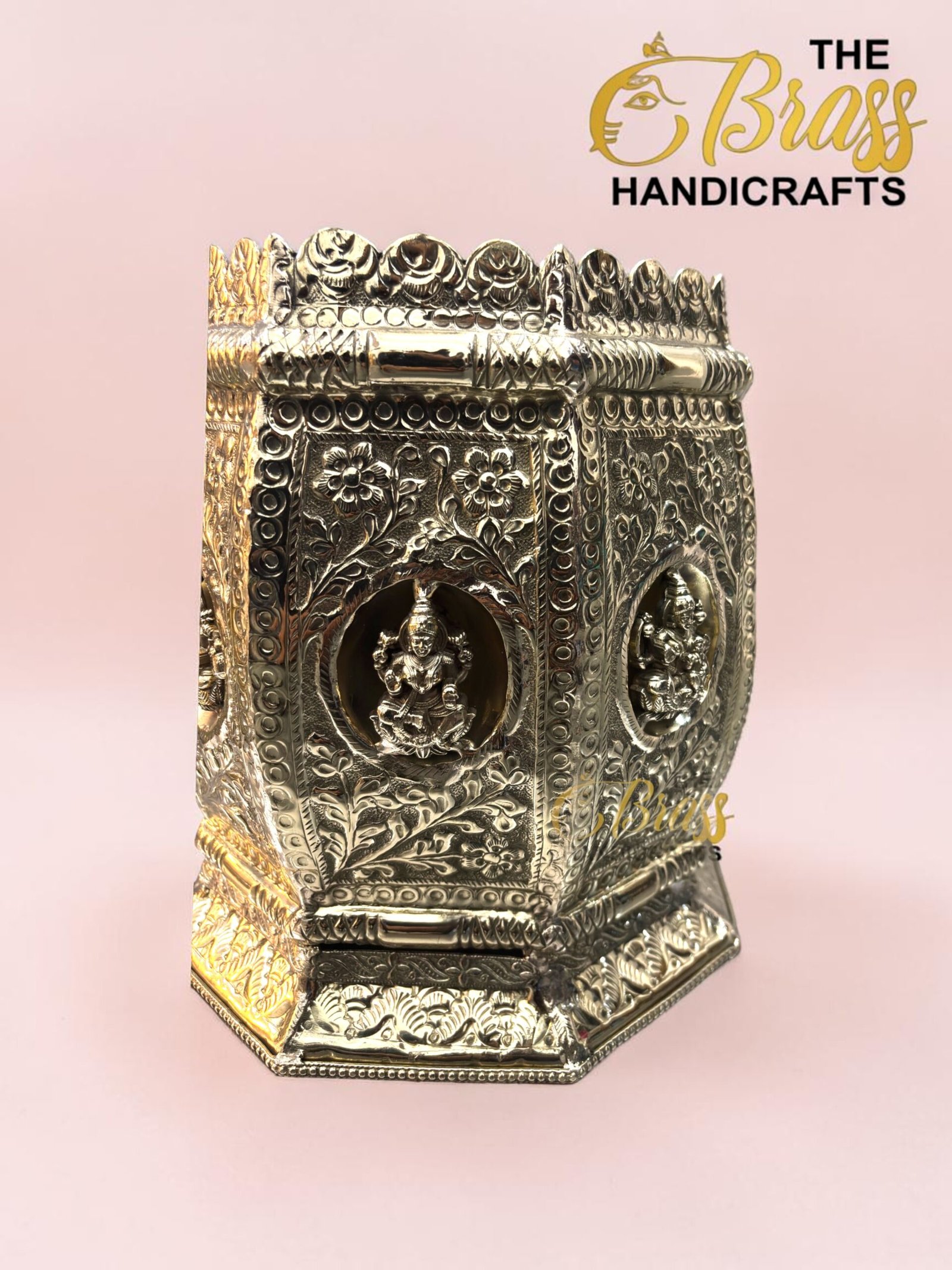Ornate silver metal box with floral engravings and raised borders, set on a pink backdrop; brand logo 'The Brass Handicrafts' visible.  thebrasshandicrafts.com