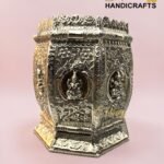 Ornate silver metal box with floral engravings and decorative edging, set against a pale pink background.  thebrasshandicrafts.com