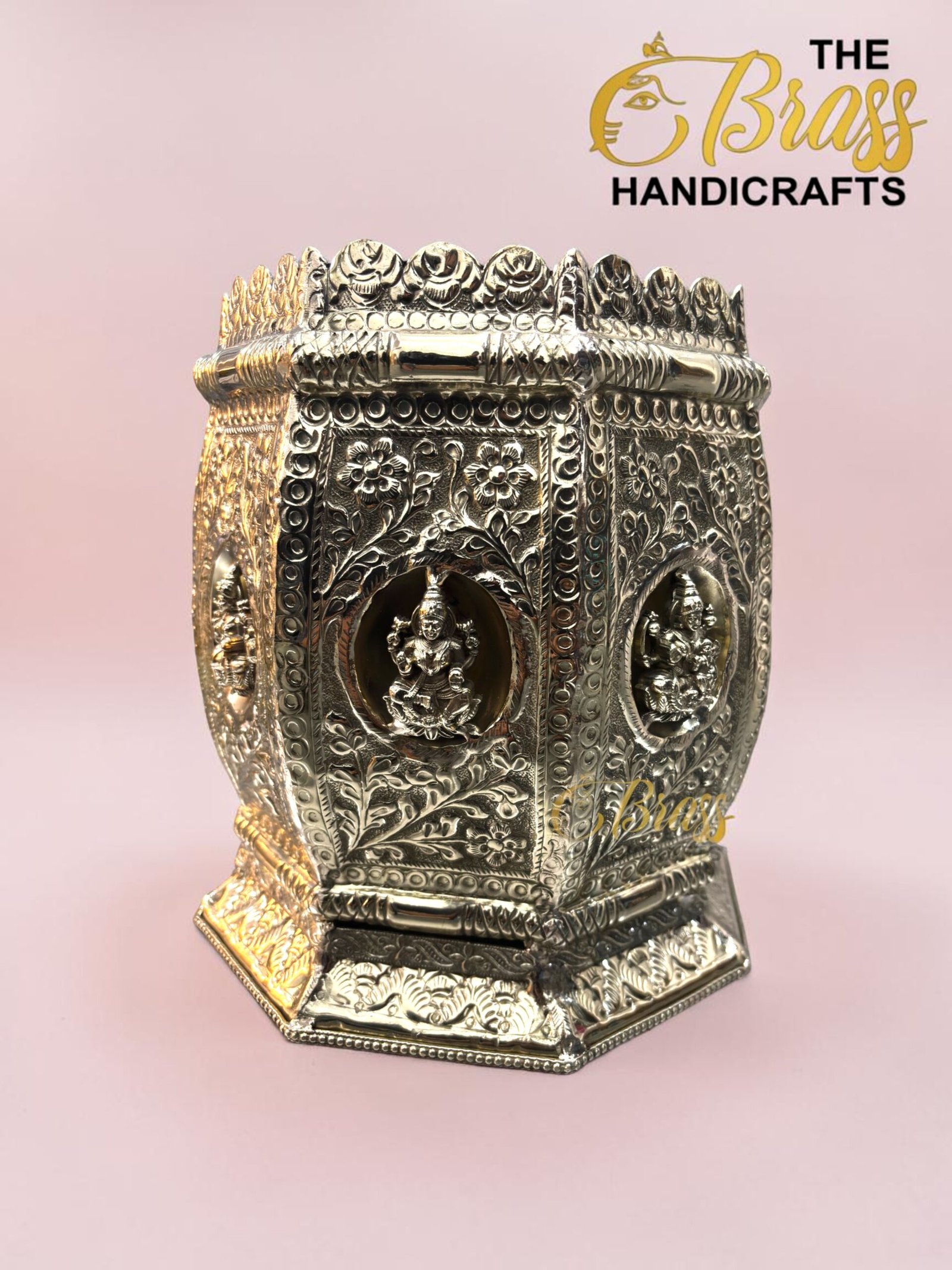 Ornate silver metal box with floral engravings and decorative edging, set against a pale pink background.  thebrasshandicrafts.com