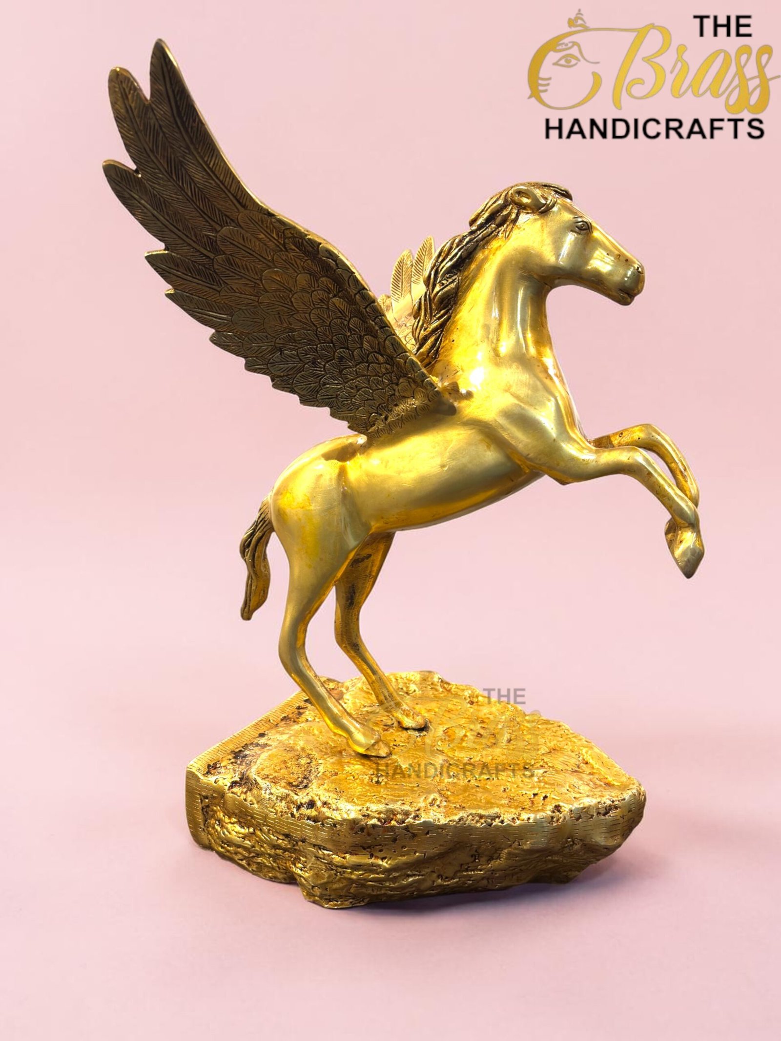 Golden Pegasus statue with wings extended on a textured pedestal, pink background and The Brass Handicrafts logo in the corner.  thebrasshandicrafts.com