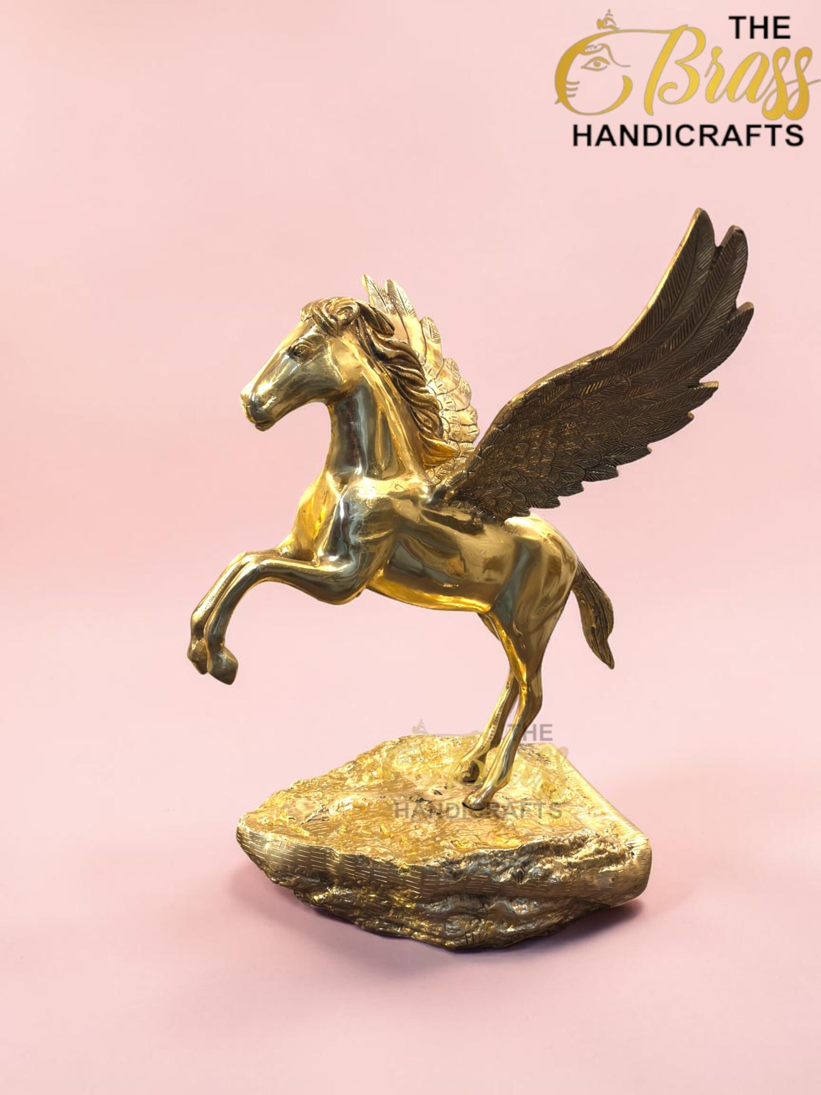 Gold Pegasus statue with wings on a rocky base against a pink background, featuring The Brass Handicrafts logo in the corner.  thebrasshandicrafts.com