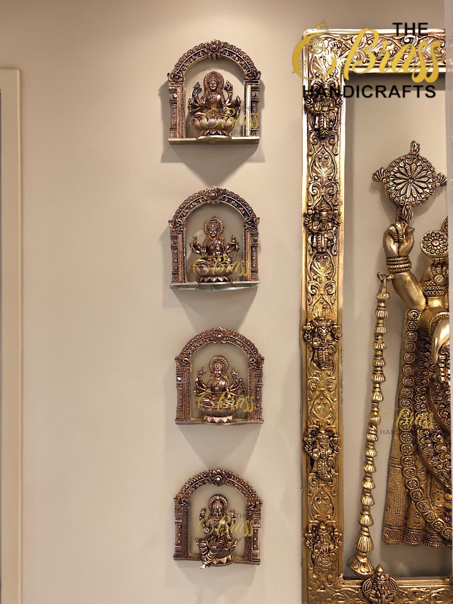 Metal decorative Hindu deities in ornate arched niches mounted on a beige wall, with a tall gold ornamental frame to the right  thebrasshandicrafts.com