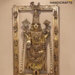 Ornate metal statue of a Hindu goddess with elaborate jewelry, set inside a heavily carved decorative frame.  thebrasshandicrafts.com