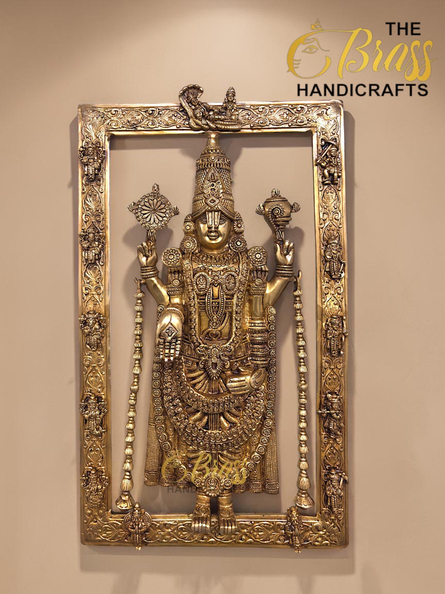 Ornate metal statue of a Hindu goddess with elaborate jewelry, set inside a heavily carved decorative frame.  thebrasshandicrafts.com