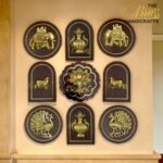 Row of gold embossed handicraft plaques on dark frames featuring elephant, vase, peacock and floral motifs at display wall  thebrasshandicrafts.com