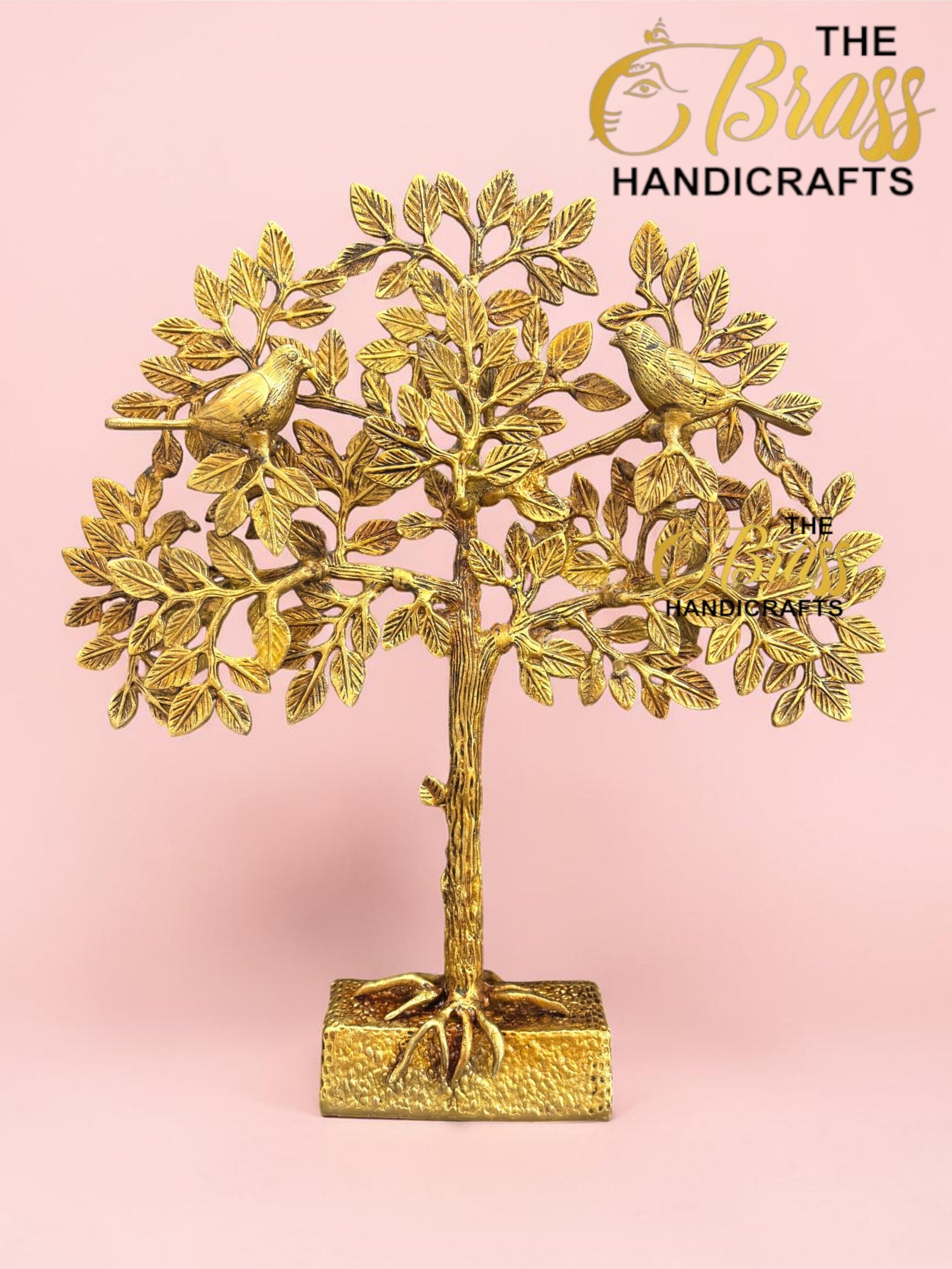 Gold metal tree sculpture with two birds perched on braided branches, set on a square base against a pink backdrop, branded The Brass Handicrafts in the corner.  thebrasshandicrafts.com