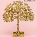Gold metal tree sculpture with two birds perched on branching limbs against a pink backdrop, branded 'The Brass Handicrafts' in the corner  thebrasshandicrafts.com