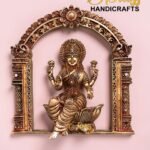 Gold-toned Hindu goddess statue set in an ornate carved arch on a pink background (The Brass Handicrafts).  thebrasshandicrafts.com