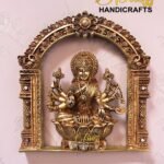 Gold-toned Lakshmi statue seated on a lotus, inside an ornate arch, with 'The Bliss Handicrafts' logo in the top right.  thebrasshandicrafts.com