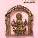 Ornate gold brass statue framed by a carved arch, set against a pink background; logo reads The Brass Handicrafts in the corner.  thebrasshandicrafts.com