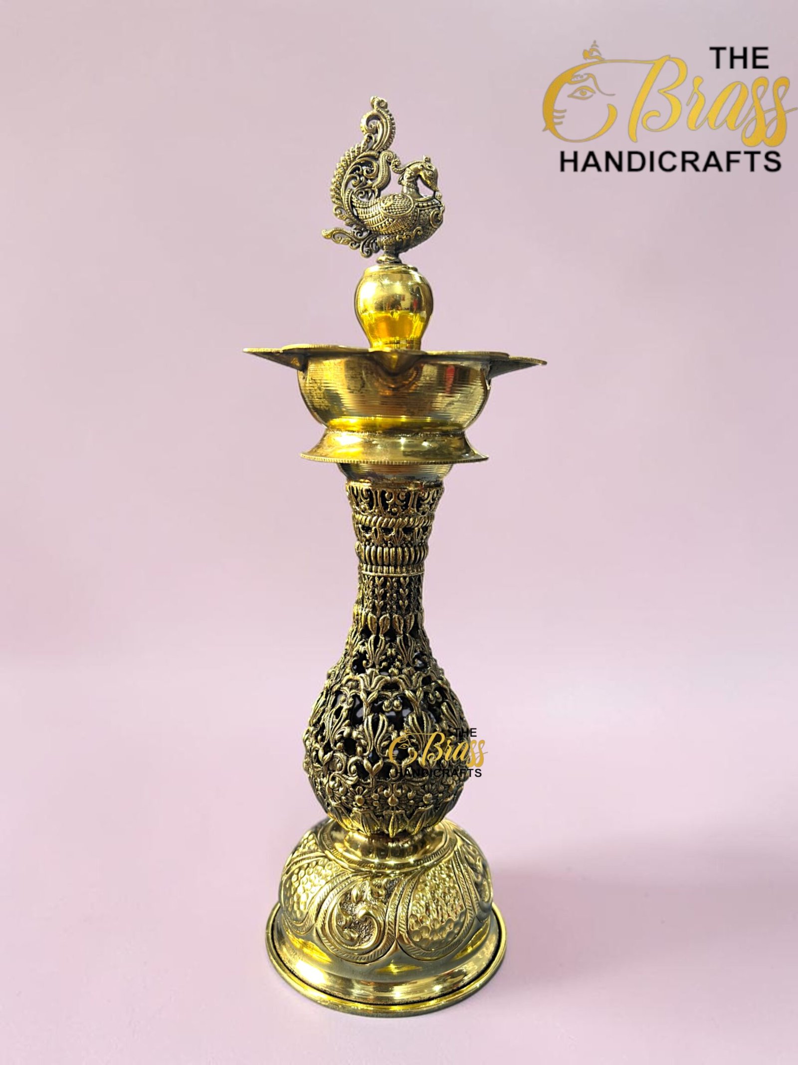 Intricately carved brass decorative piece with an ornate bird finial atop, set against a pink background. (Brand: The Brass Handicrafts)  thebrasshandicrafts.com