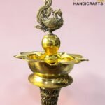 Ornate brass hookah with a peacock finial against a pink background; 'The Brass Handicrafts' logo in the corner.  thebrasshandicrafts.com