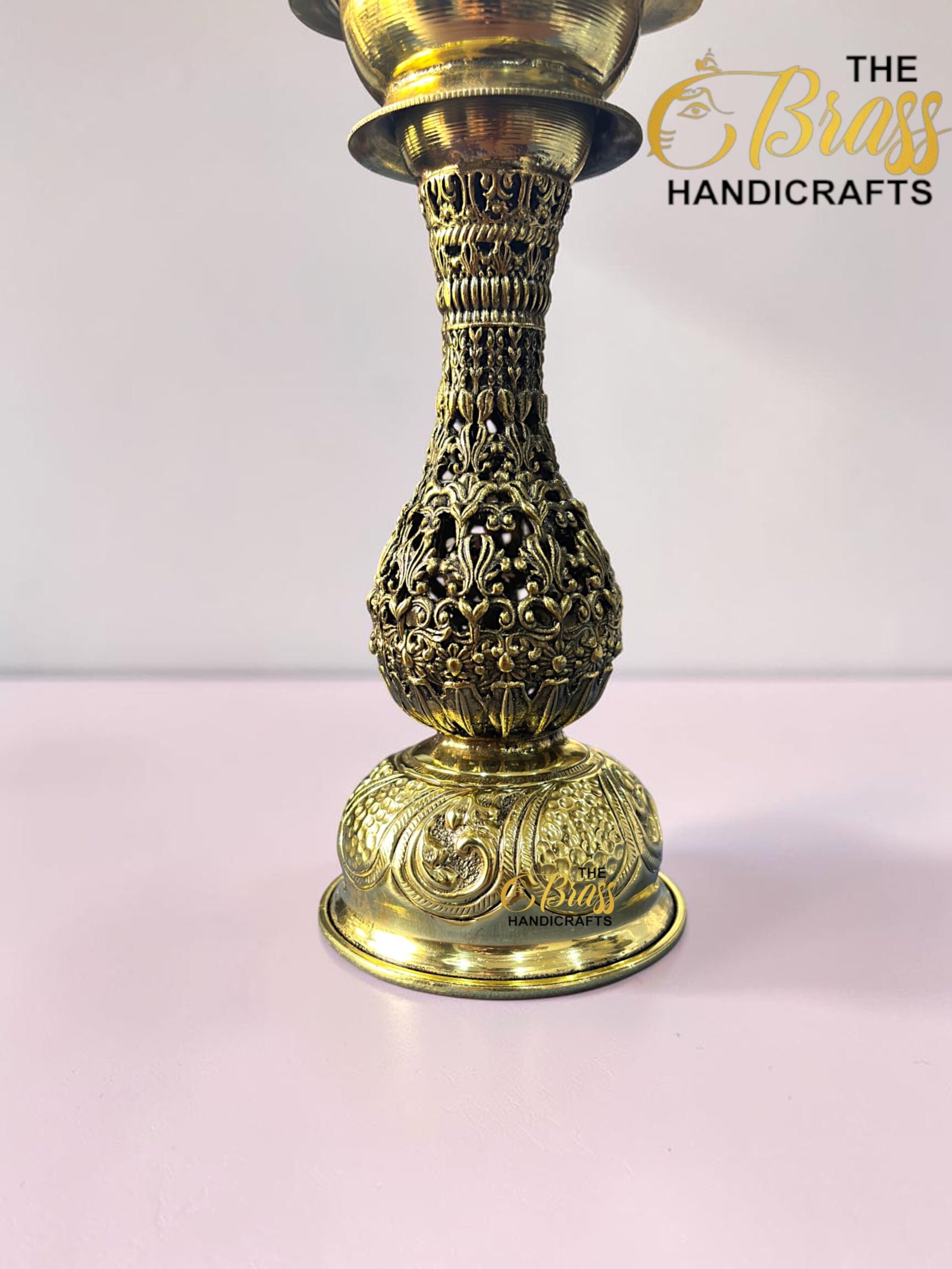 Ornate gold-hookah base with intricate filigree on a pink surface, logo 'The Brass Handicrafts' in the lower right corner.  thebrasshandicrafts.com