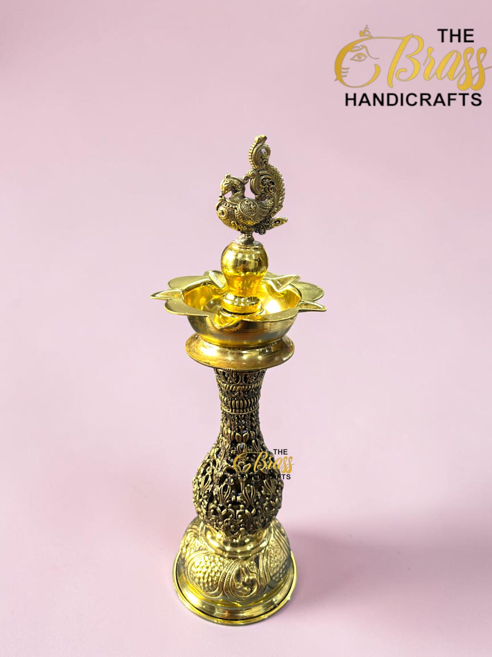 Decorative, ornate brass hookah with a detailed top finial against a pink background.  thebrasshandicrafts.com