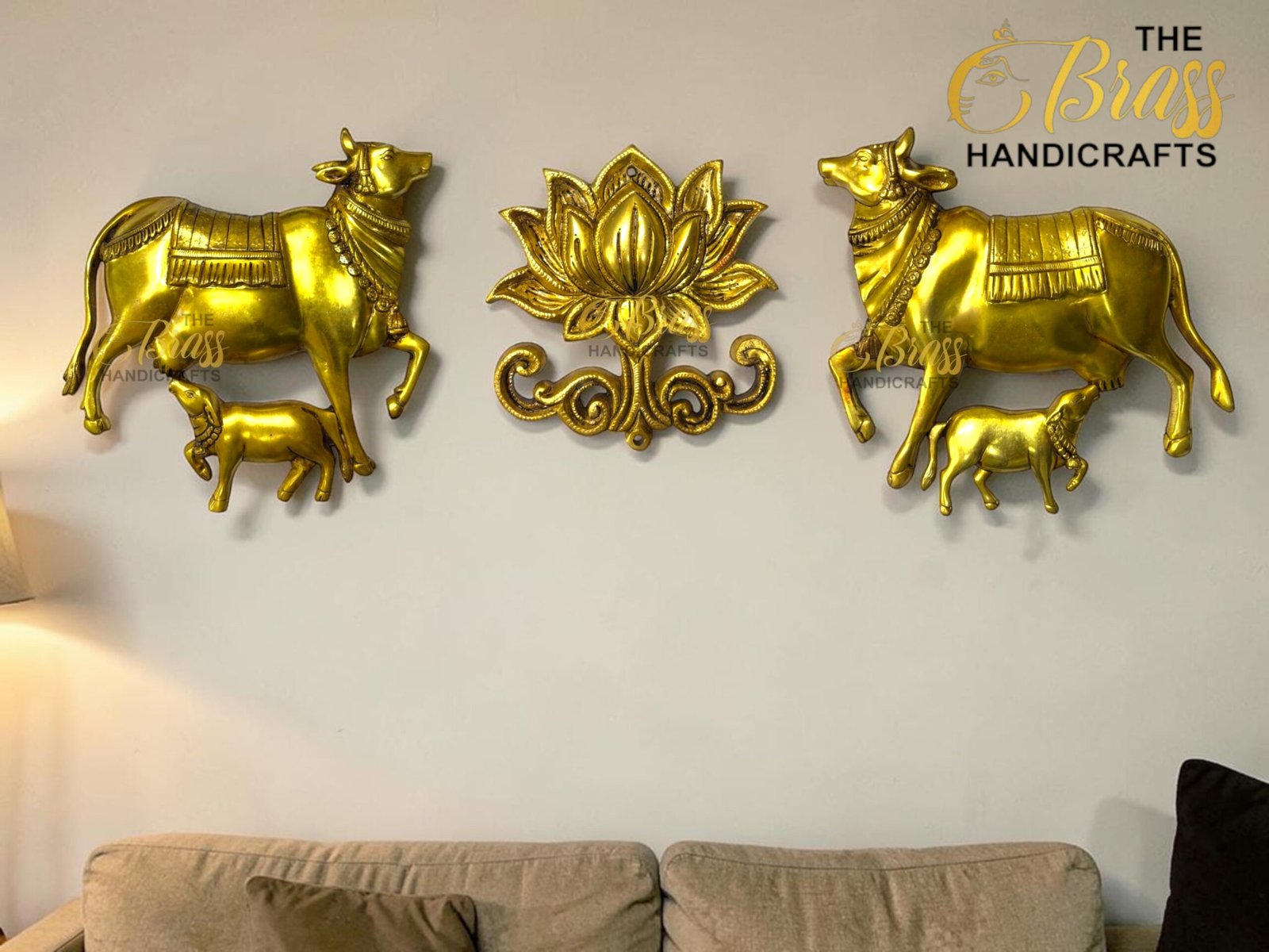 Golden wall sculpture: two golden cows on either side of a central ornate lotus motif, mounted above a beige sofa.  thebrasshandicrafts.com