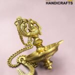 Close-up of a gold ornate brass hookah top with intricate filigree against a pink background, chain draped nearby  thebrasshandicrafts.com