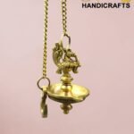 Close-up of an ornate brass hanging oil lamp suspended by a chain, showing intricate decorative detailing.  thebrasshandicrafts.com