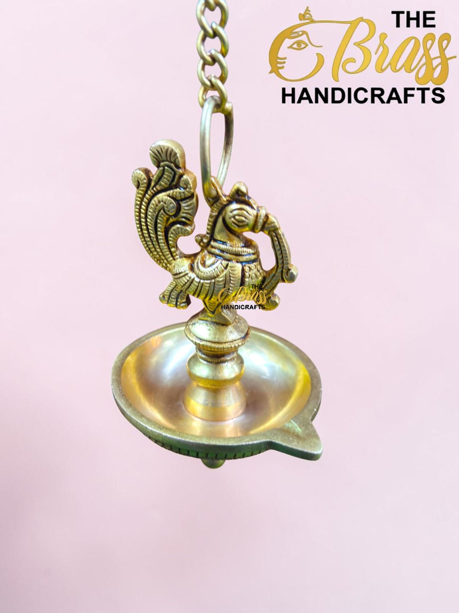 Ornate brass hanging lamp with a decorative bird-shaped finial, chain links, and a pink background.  thebrasshandicrafts.com