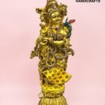 IMG_5923 - thebrasshandicrafts.com Gold ornate brass statue of a Hindu deity adorned with colorful jewels against a pink background; includes 'The Brass Handicrafts' logo in the corner. thebrasshandicrafts.com