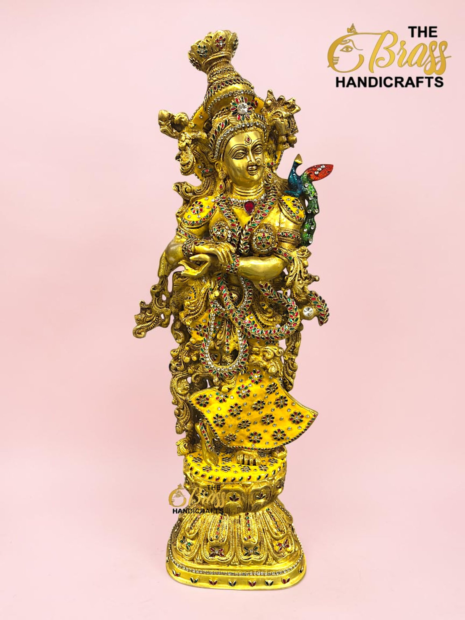 IMG_5923 - thebrasshandicrafts.com Gold ornate brass statue of a Hindu deity adorned with colorful jewels against a pink background; includes 'The Brass Handicrafts' logo in the corner. thebrasshandicrafts.com