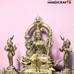 Gold brass Hindu deity statue with smaller figures arranged around it, set against a pink backdrop.  thebrasshandicrafts.com