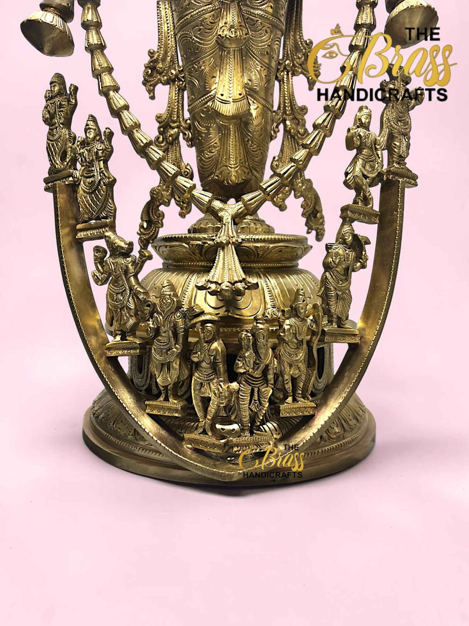 Intricately detailed brass Hindu deity statue with multiple figures, set against a pink background.  thebrasshandicrafts.com