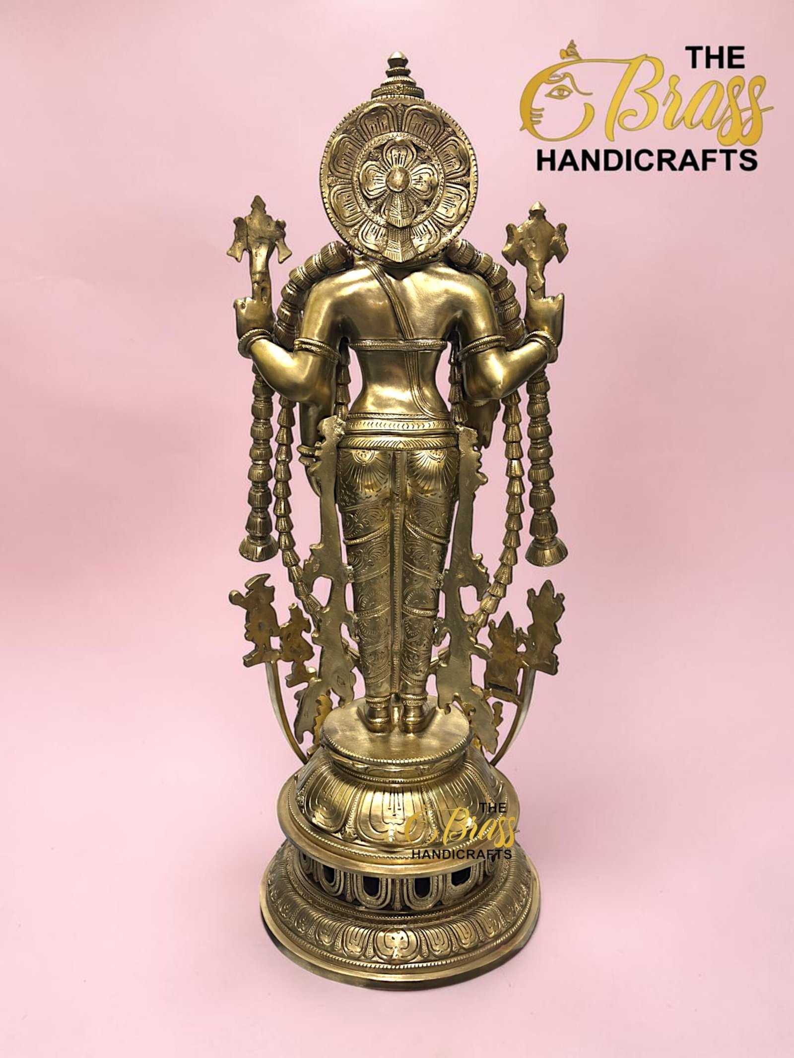 Back view of a gold brass multi-armed statue with ornate headdress against a pink background, part of The Brass Handicrafts product line.  thebrasshandicrafts.com