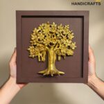Gold tree relief mounted in a brown square frame, held by two hands against a beige background.  thebrasshandicrafts.com