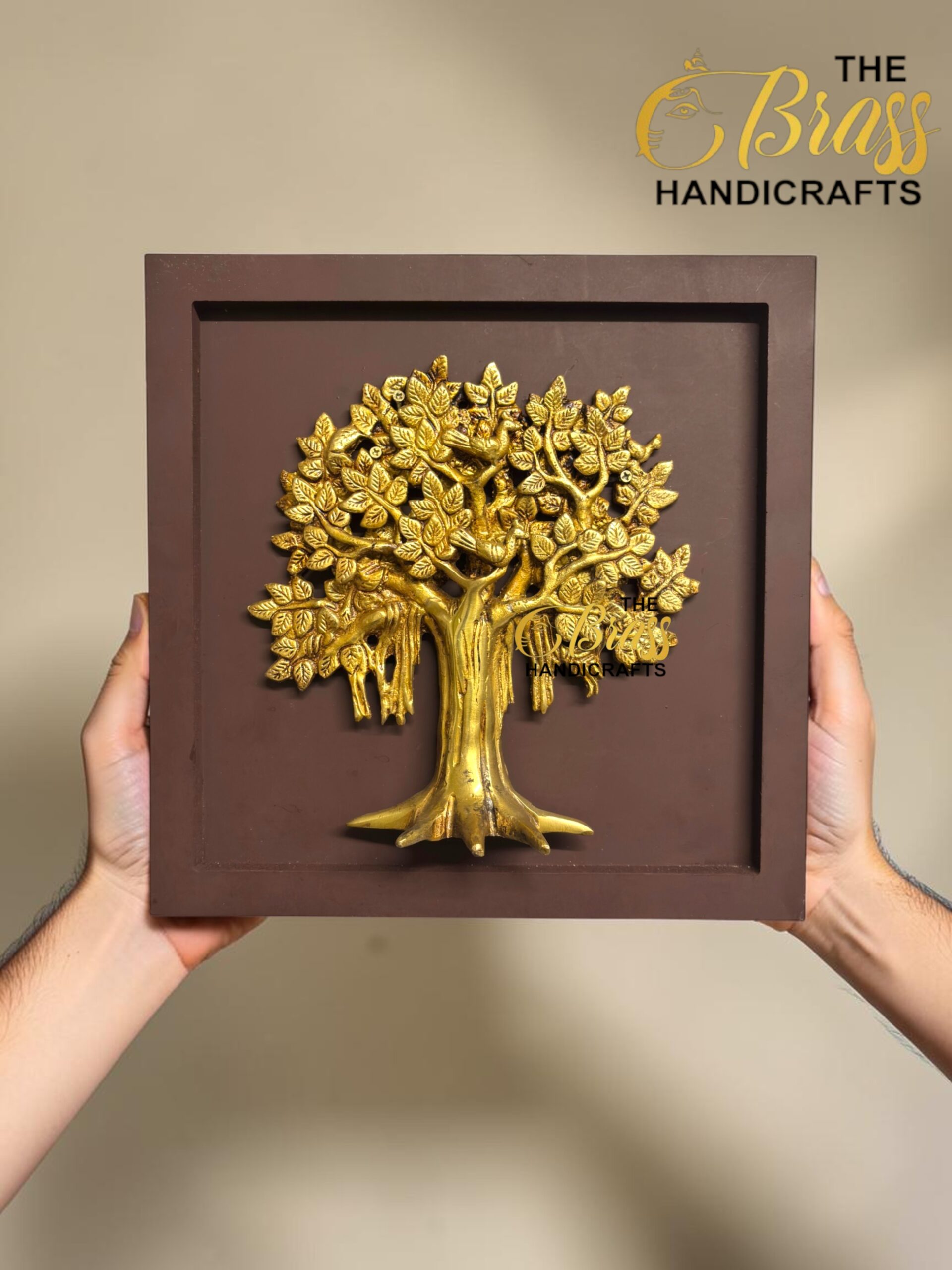 Gold tree relief mounted in a brown square frame, held by two hands against a beige background.  thebrasshandicrafts.com