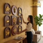 Woman decorating a wall with gold embossed plaques in dark frames in a showroom setting.  thebrasshandicrafts.com