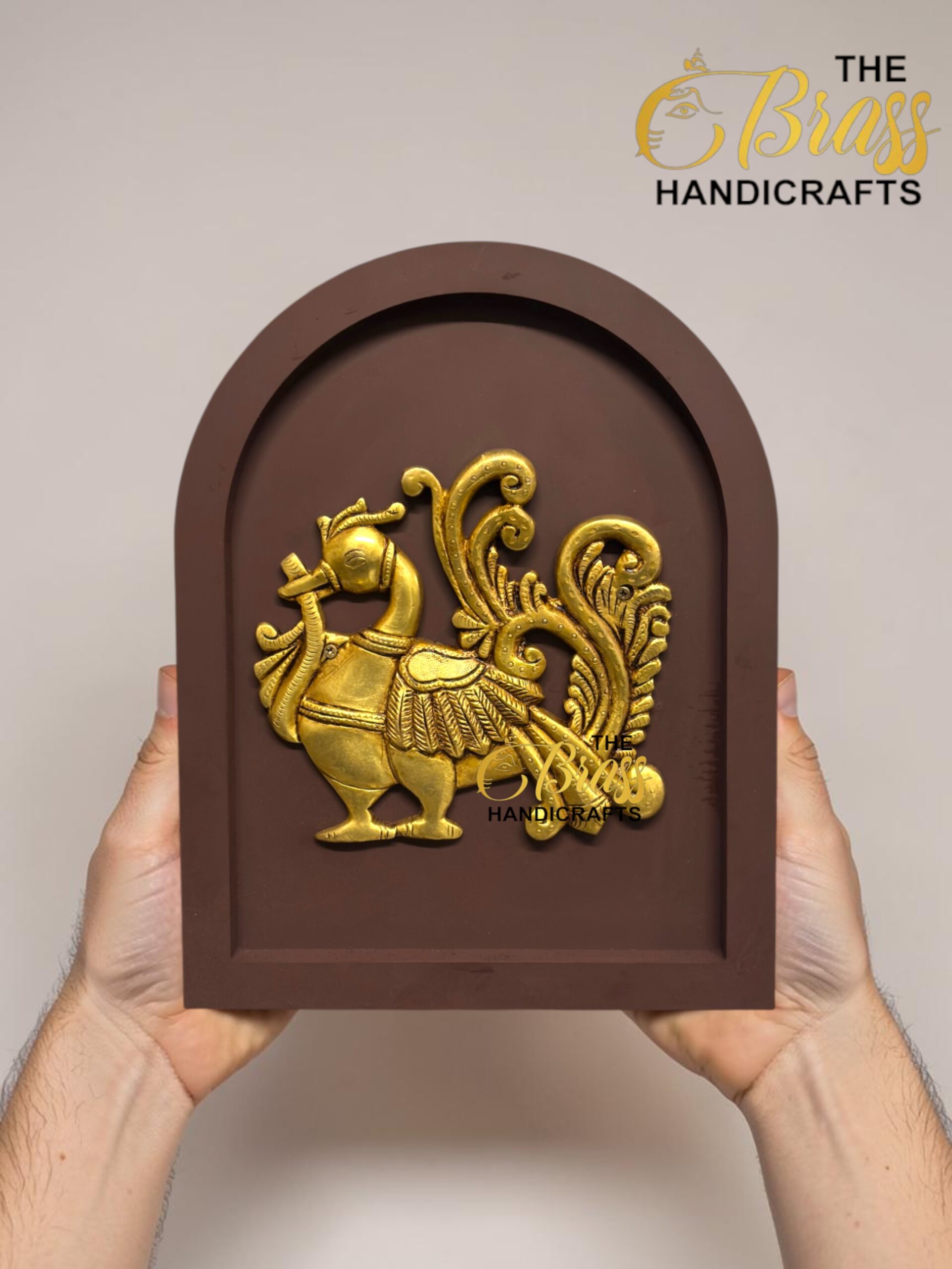 Brown arched plaque featuring a gold ornate mythical horse with wings being held by two hands. The watermark 'The Brass Handicrafts' is visible.  thebrasshandicrafts.com