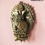 IMG_6158 - thebrasshandicrafts.com Decorative brass sculpture with intricate patterns and crown, set against a pink wall. thebrasshandicrafts.com