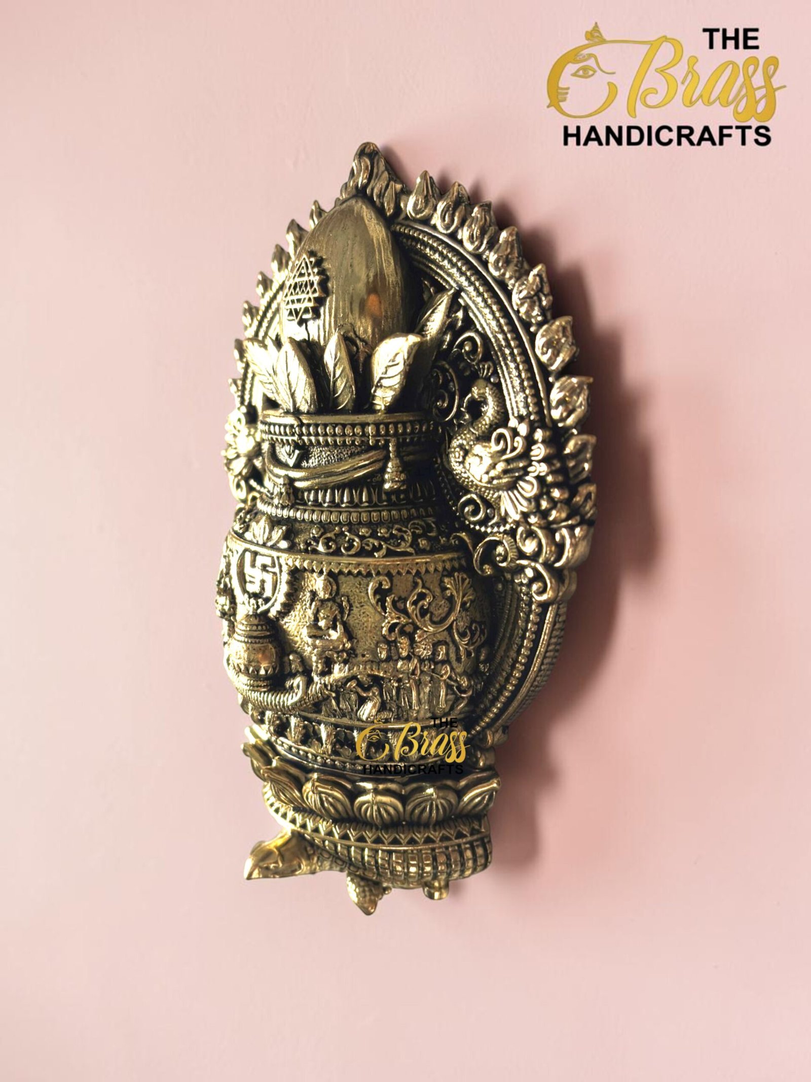 IMG_6163 - thebrasshandicrafts.com Ornate brass decorative sculpture with a crown-like top and intricate floral and geometric motifs against a pink background, branding visible at bottom right. thebrasshandicrafts.com